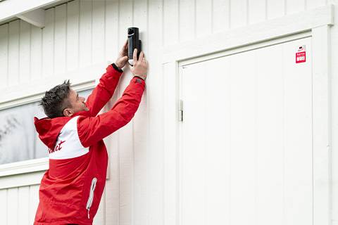 Instalador montando detector perimetral en fachada casa